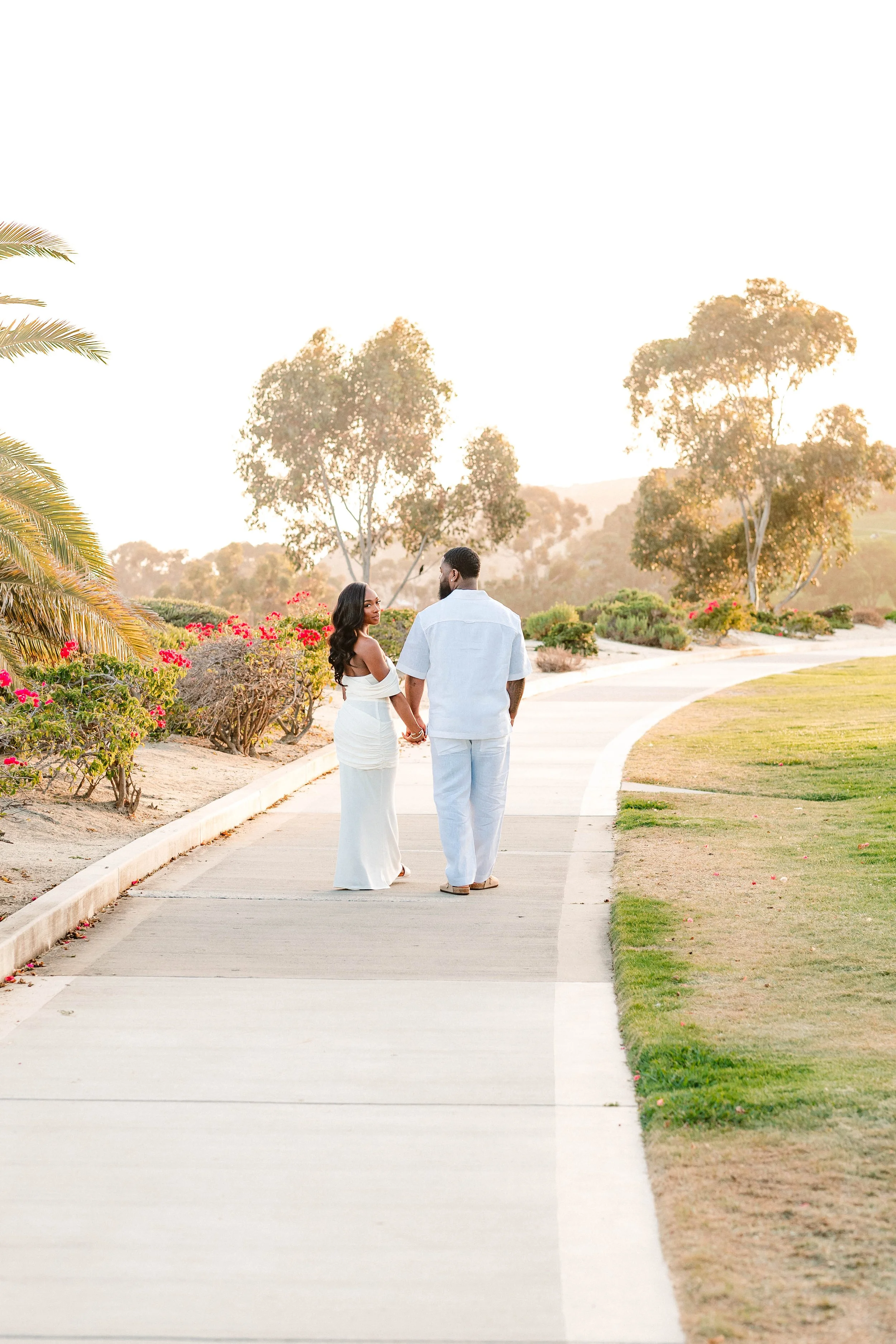 Couple walks away from camera during golden hour, Dana Point, California