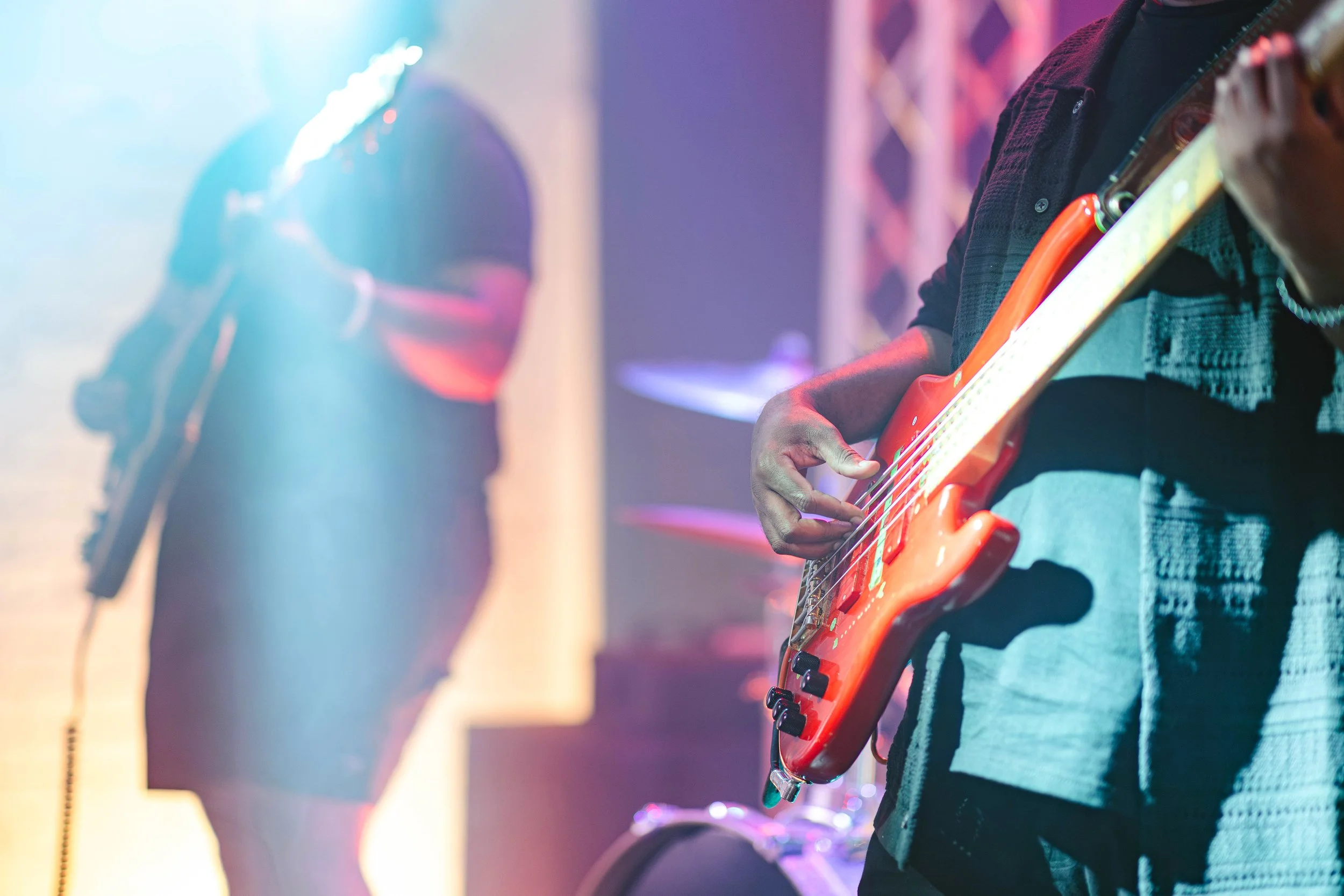 Musicians playing electric guitars on stage with colorful lights.
