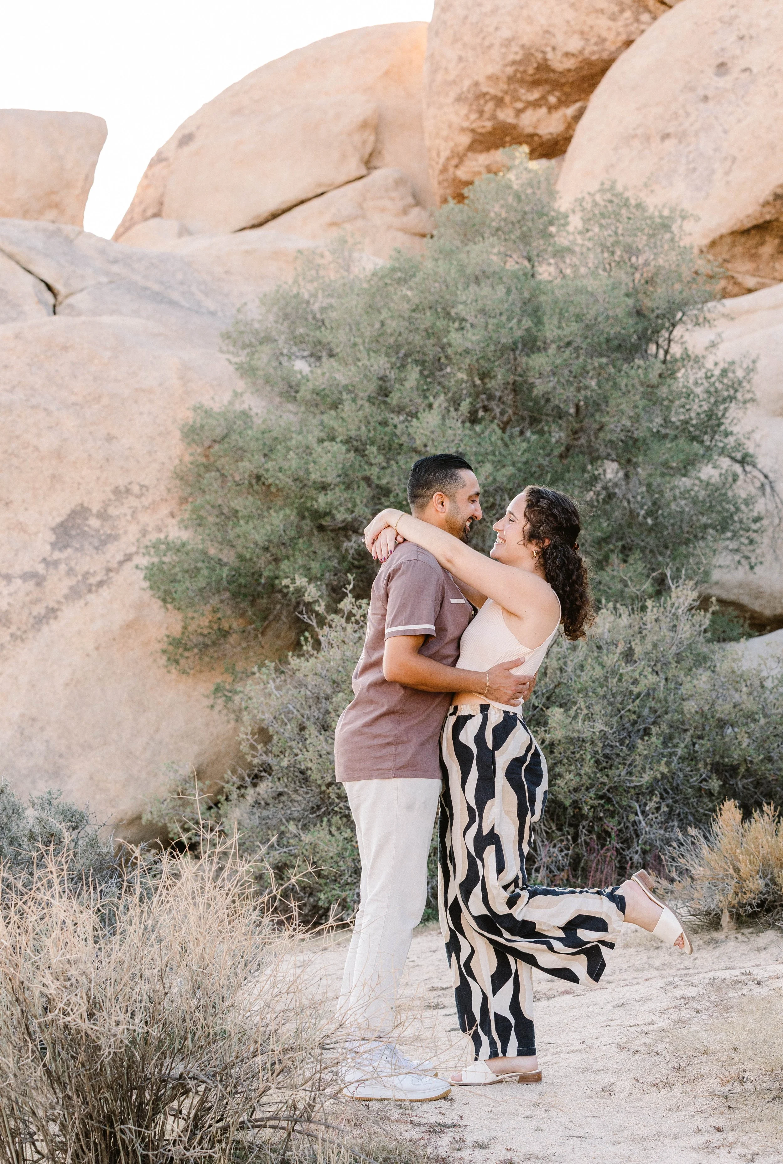 Couple embraces surrounded by desert foliage and rocks