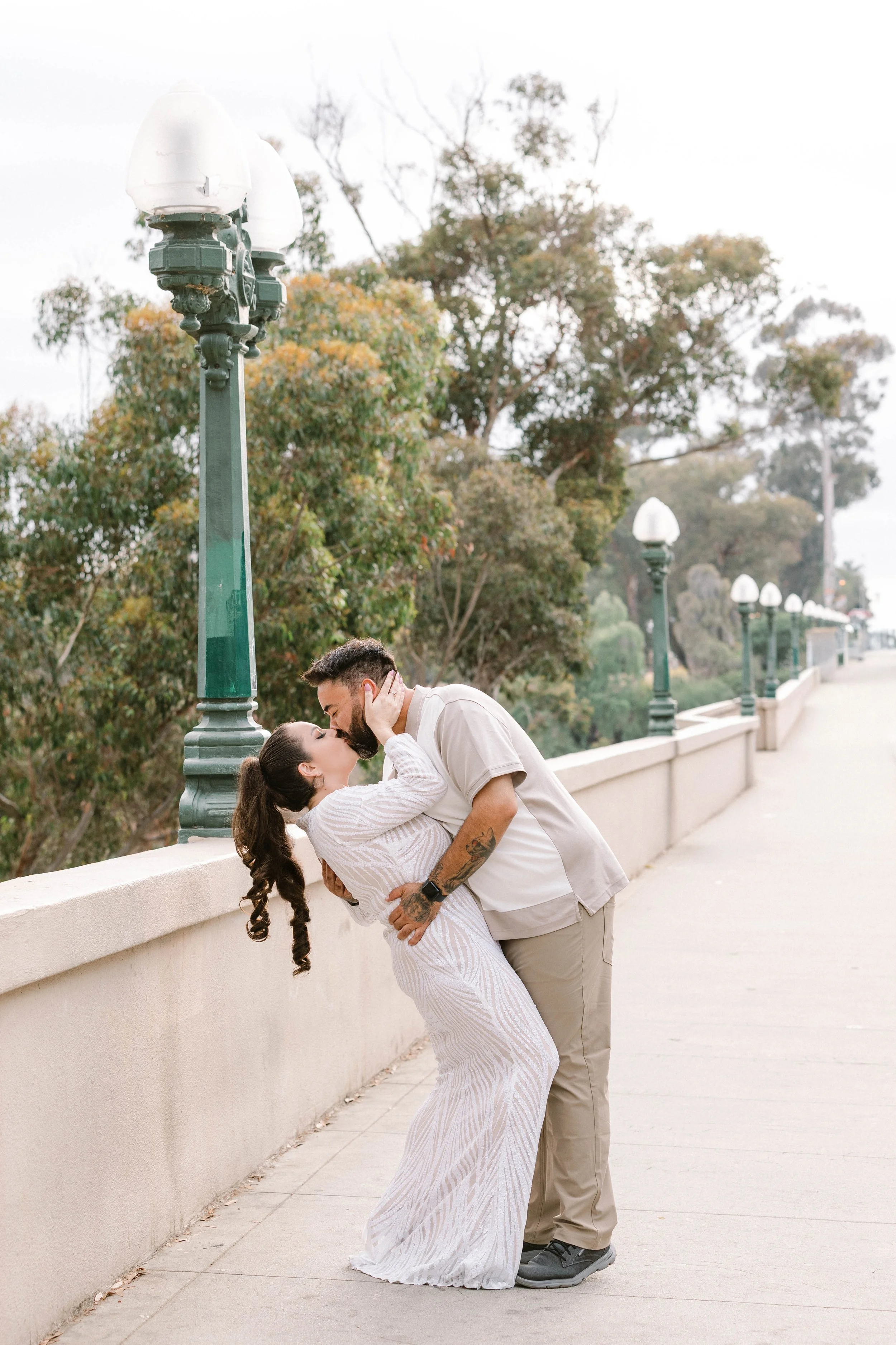 Engagement portrait of man dipping and kissing his fiancé at Balboa Park in San Diego