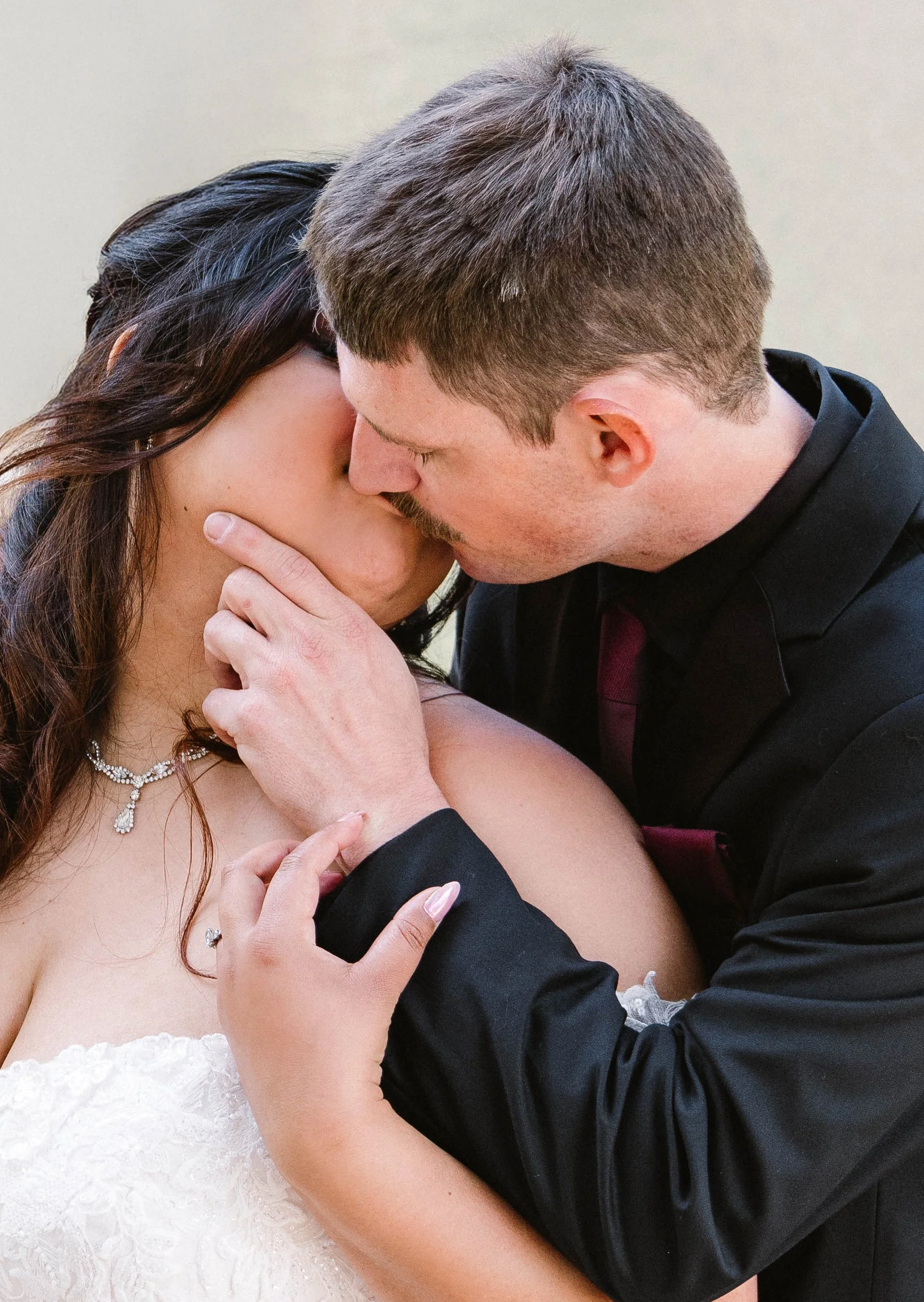 A man and woman sharing a kiss, with the man holding the woman's chin. They are dressed in formal attire, suggesting a wedding or special occasion.