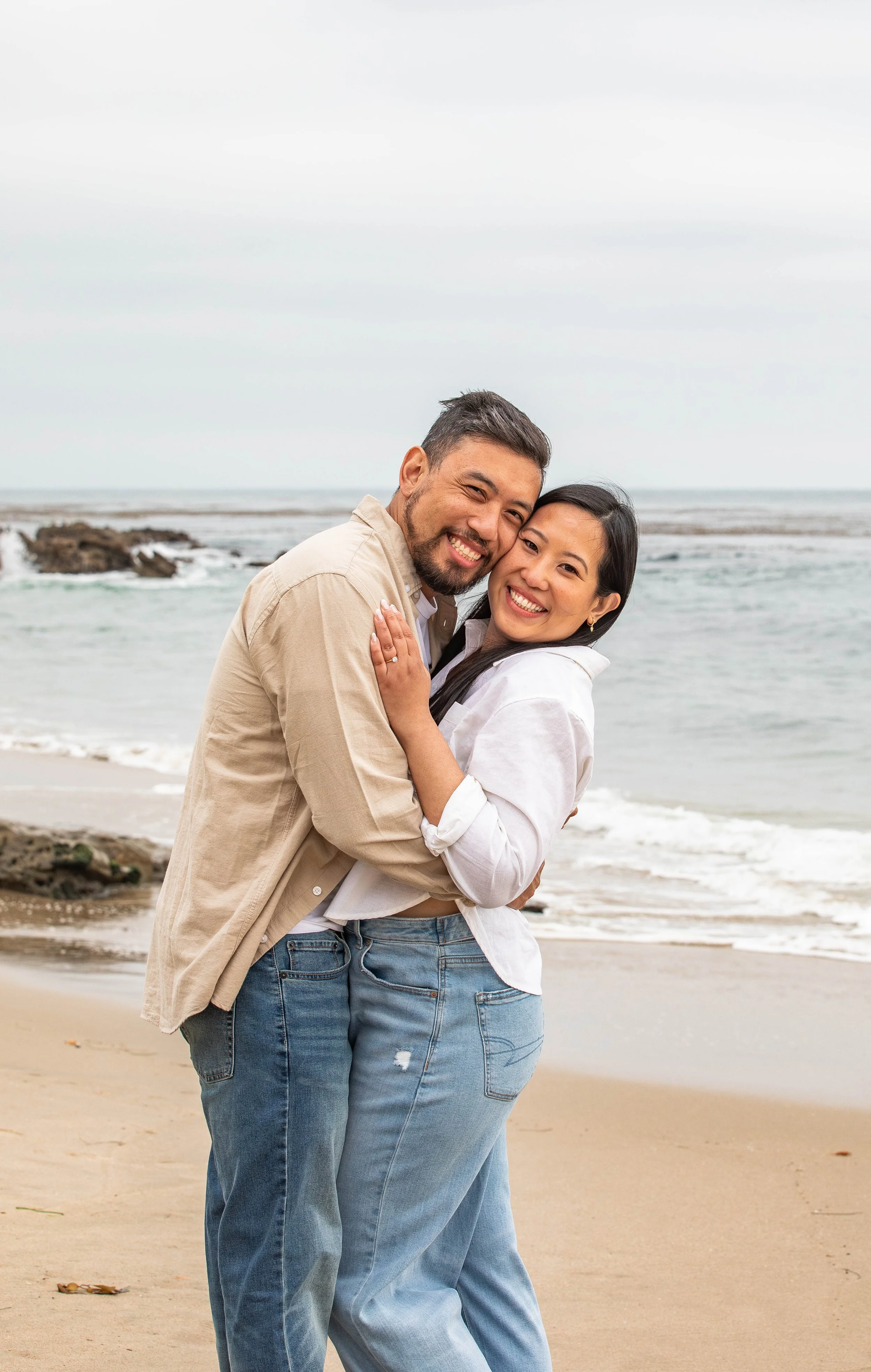 Couple embraces and smiles for the camera on the beach Laguna Beach California