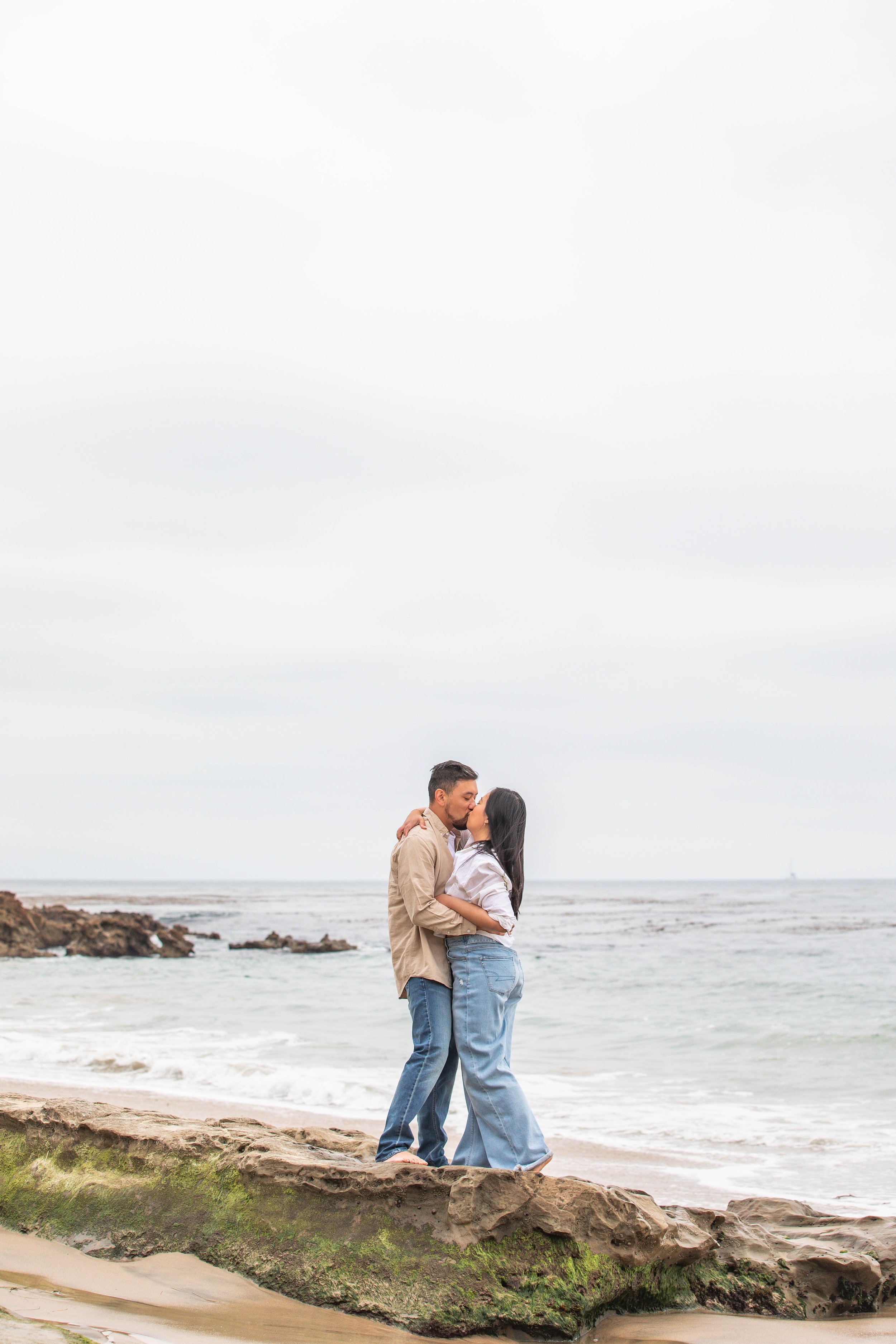Couple kisses on rocky shoreline Laguna Beach California
