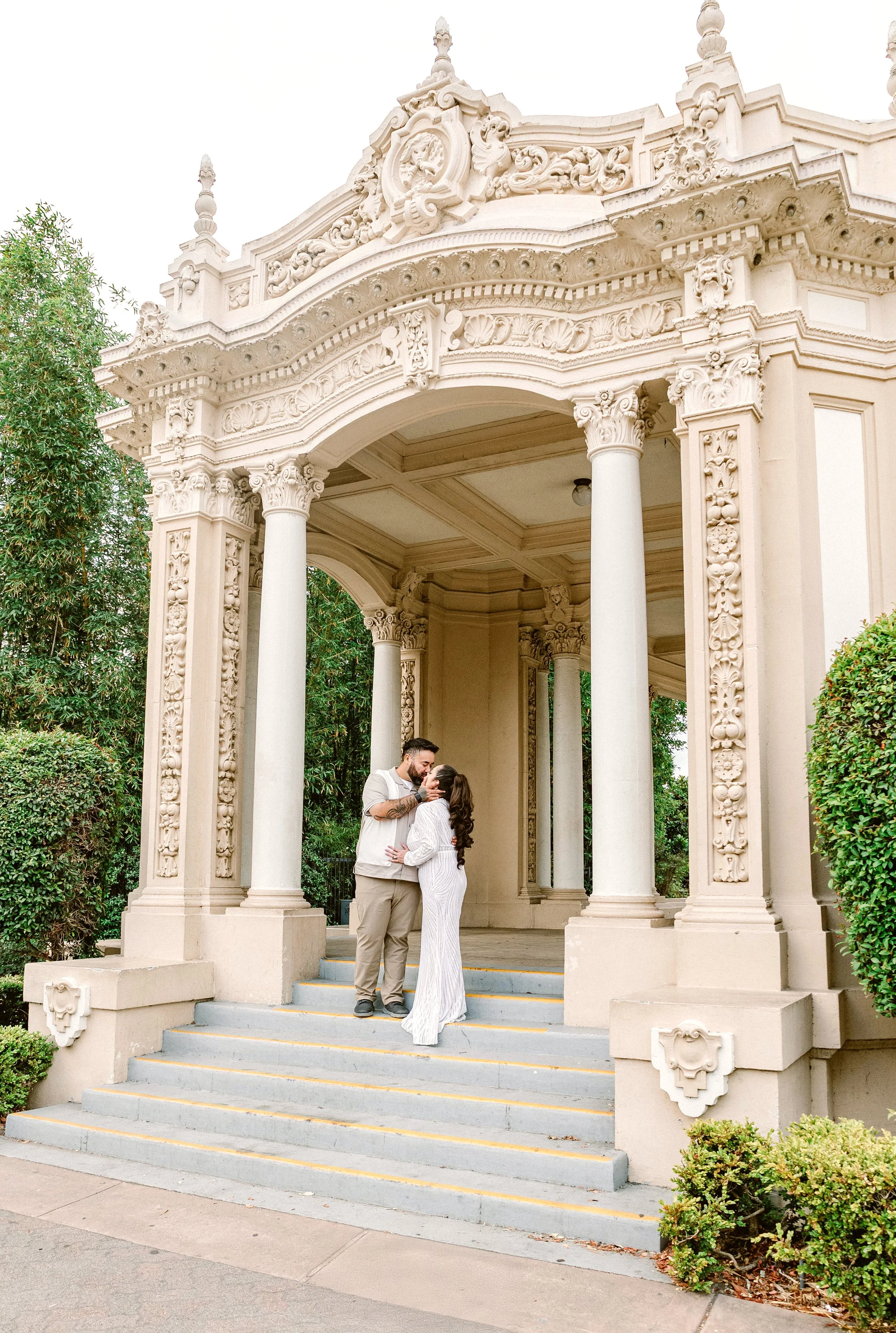 Couple kisses under ornate Spanish style arch at Balboa Park, San Diego