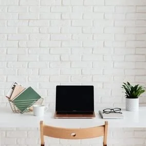 Entrepreneur online therapy session on black laptop and white desk.