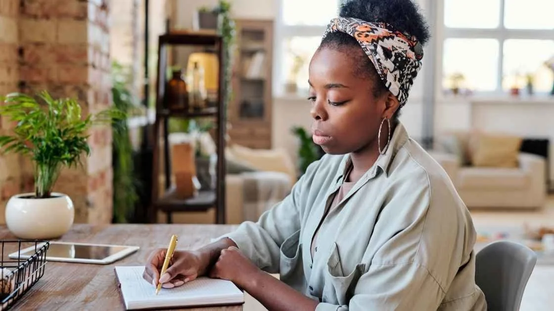 Woman writing in a journal at a desk at home