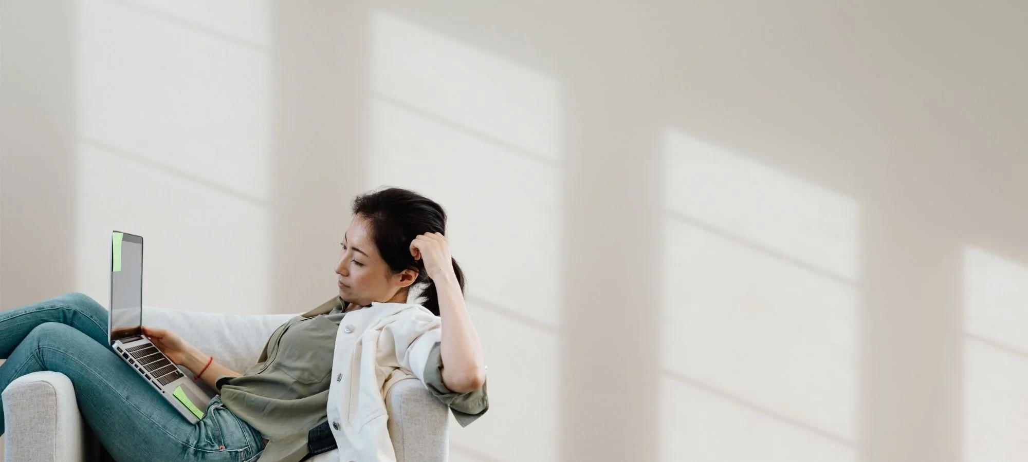 Woman lying on a couch with a laptop, looking emotionally drained