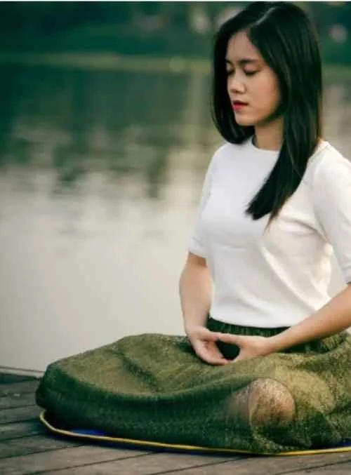 Remote worker in tech sitting outside meditating in order to work on self-esteem..