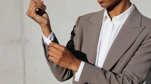 Executive woman in a grey brown suit rolling up her sleeves.