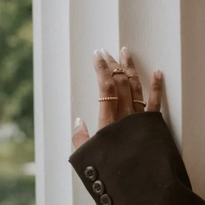 Hands resting on a window frame with rings