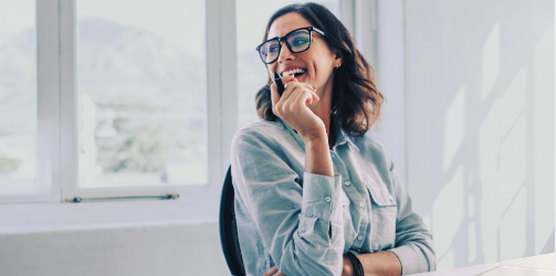 Professional woman seated at a desk during a phone call, representing online therapy for high-achieving women