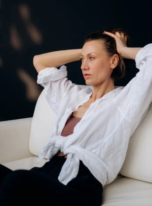 Woman sitting on a couch while feeling overwhelmed