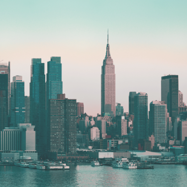 New York City skyline at sunset with buildings reflected on the water