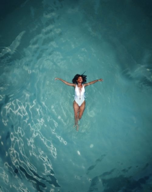 Woman floating on her back in turquoise water with arms outstretched
