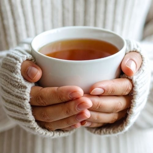 Hands holding a warm cup of tea in a quiet setting