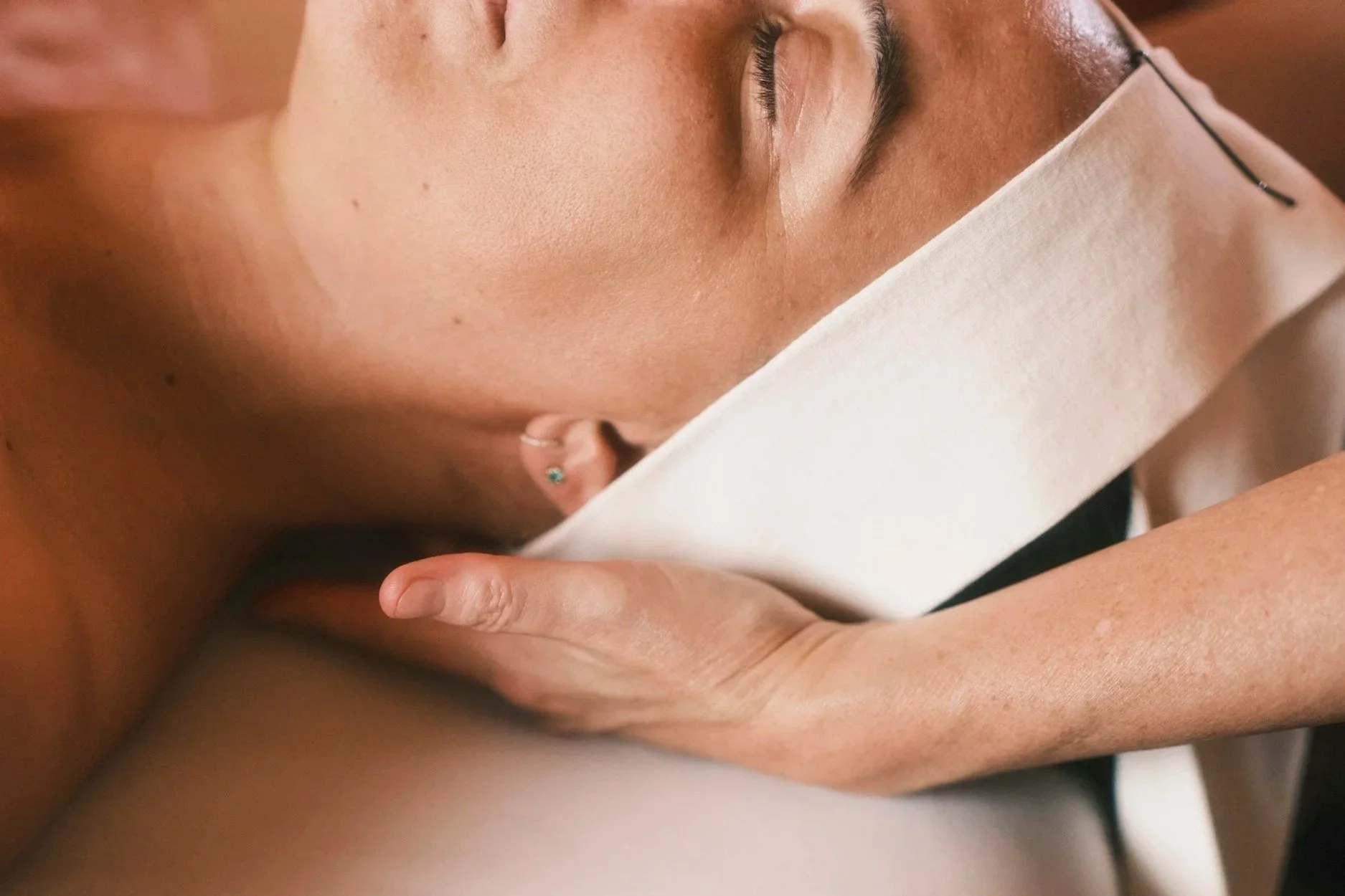 Close-up of a woman receiving a facial massage from a therapist in a spa setting.