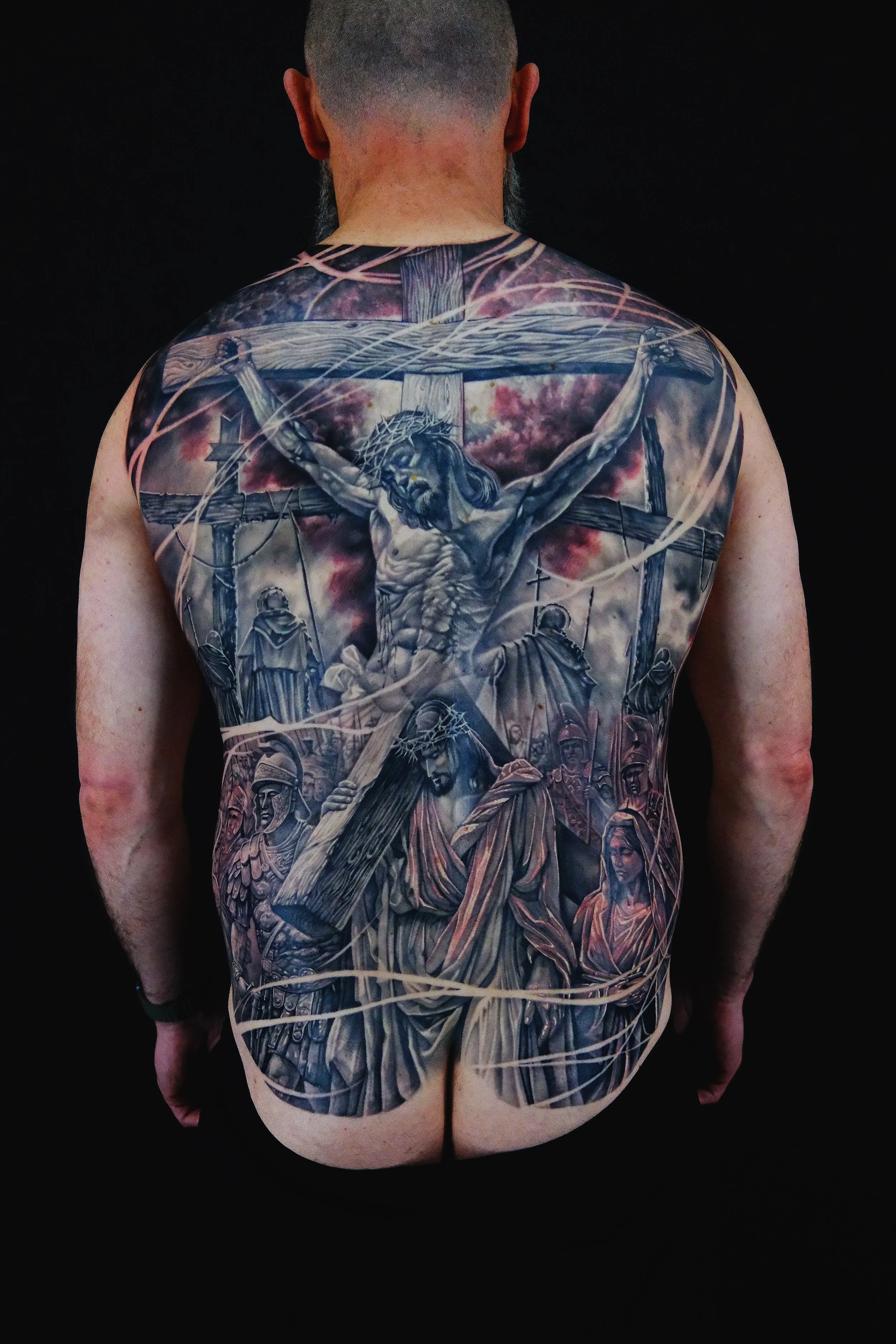 Close-up of a tattoo on a person's chest and neck featuring a realistic female face with clouds and lightning bolts surrounding it.