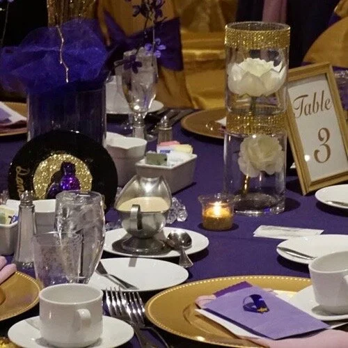 Gold table cloth on round table with purpole napkins.jpeg