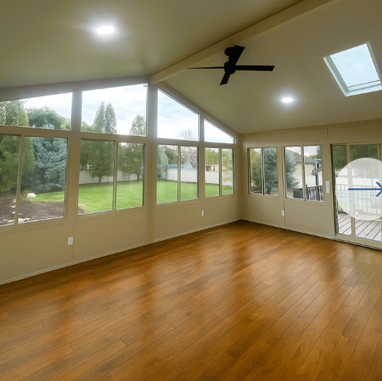 A sunroom with a wood floor and ceiling fan