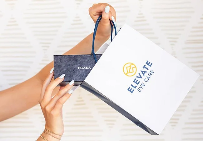 Person holding retail shopping bags from Elevate Eye Care.