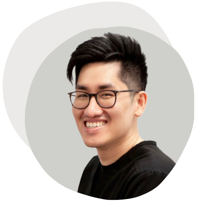 Young man with black glasses and short, styled black hair smiling at the camera.