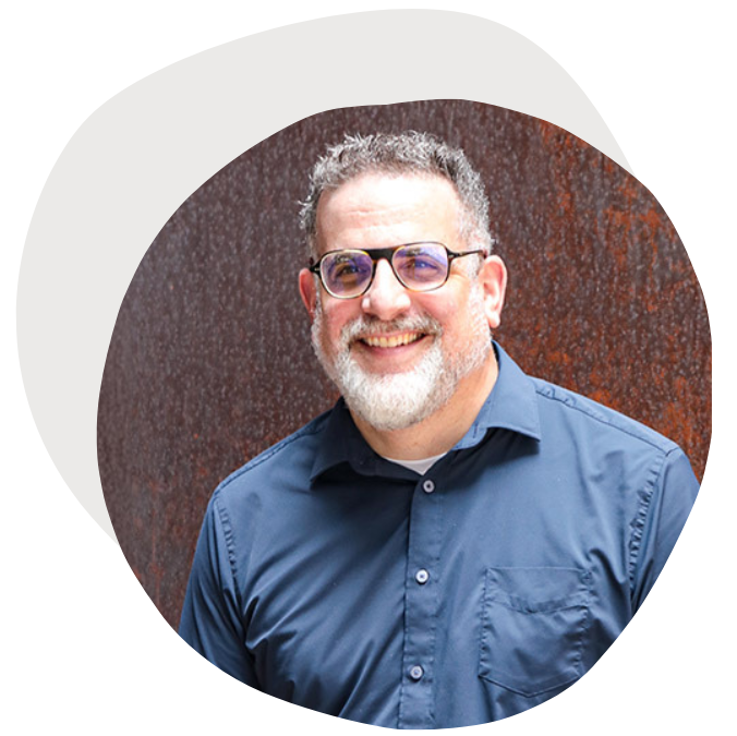 Headshot of Seth Bluenthal, a man smiling at the camera wearing a blue dress shirt.