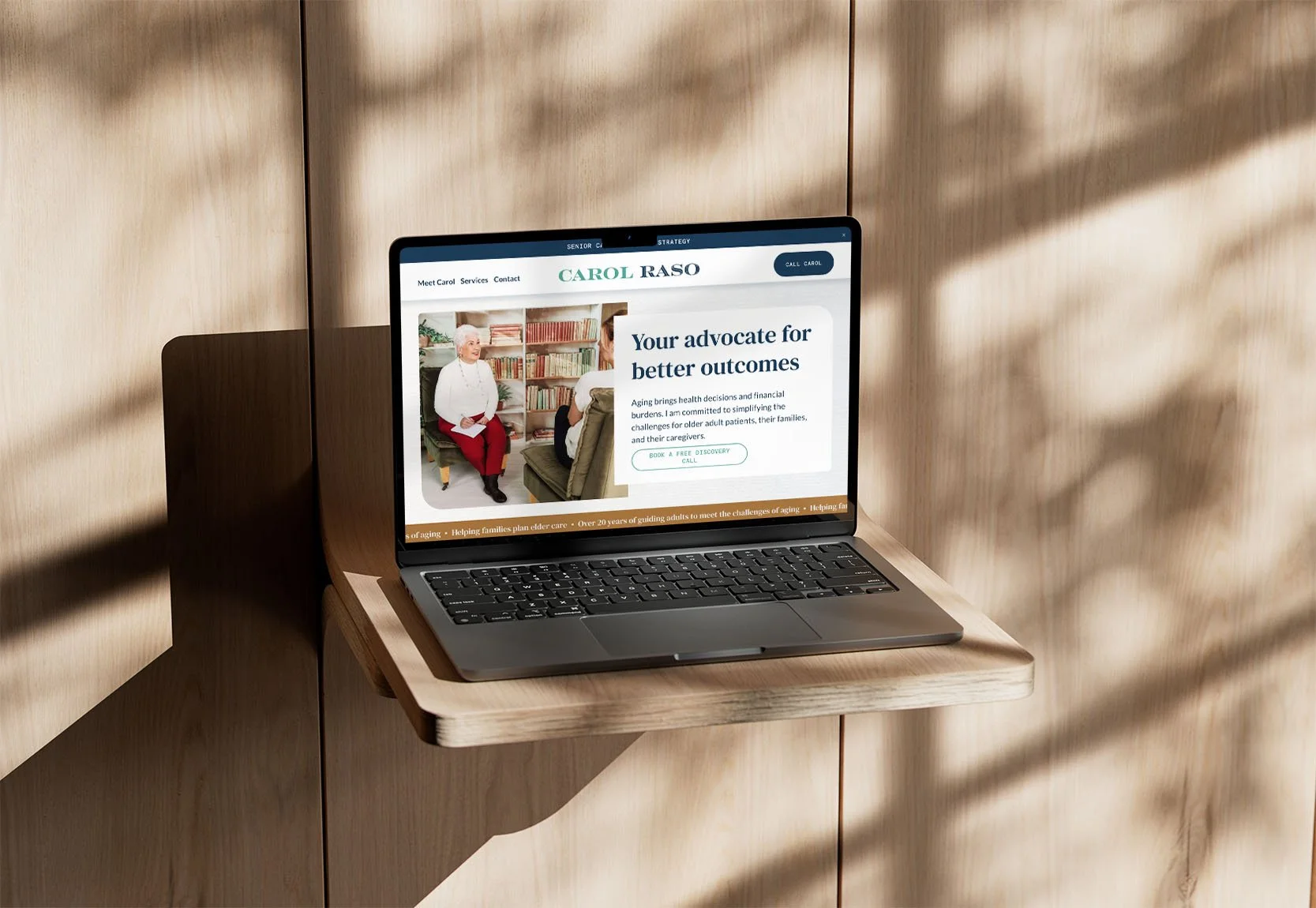 A laptop on a wooden shelf displays a website for an elder care advocacy business.
