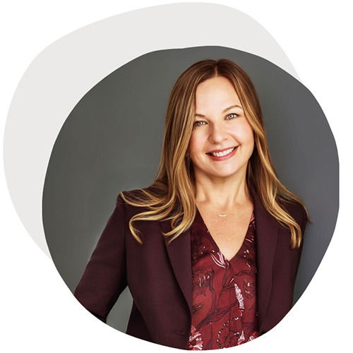 Headshot of a female with long hair, wearing a purple suit smiling at the camera