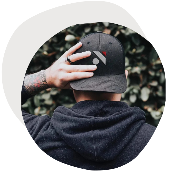 A man wearing a trucker hat backwards with a logo monogram of the letter "N".