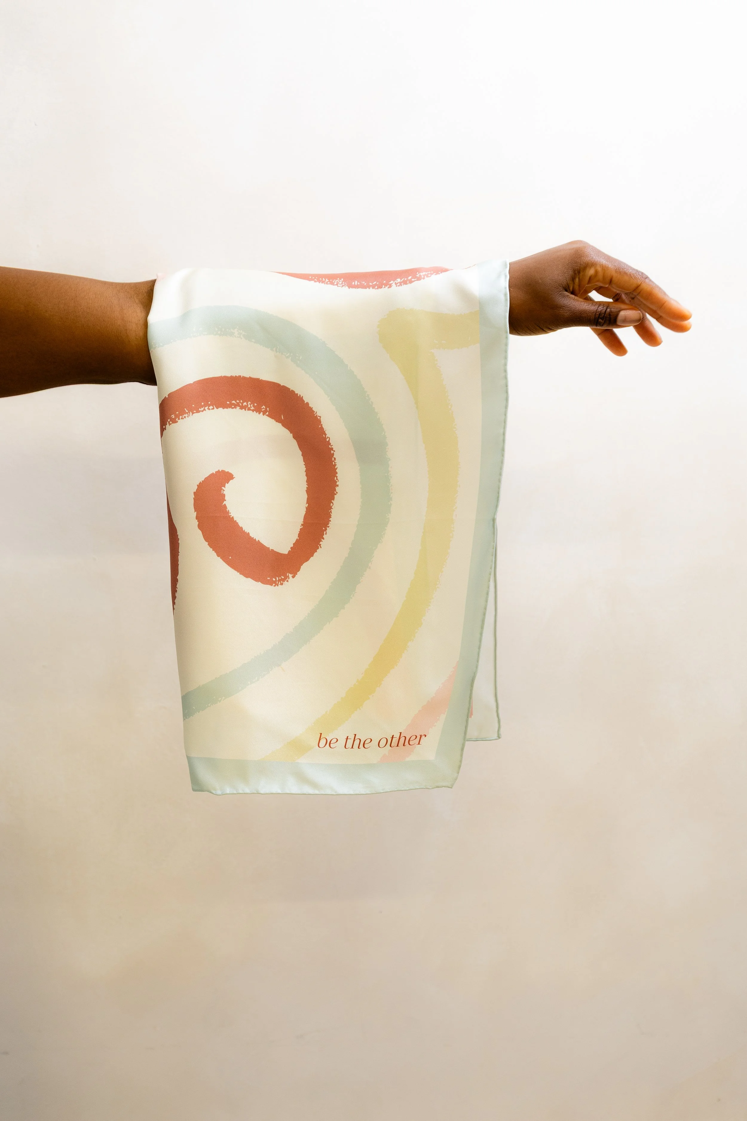 Be The Other white patterned silk scarf, draped over an arm