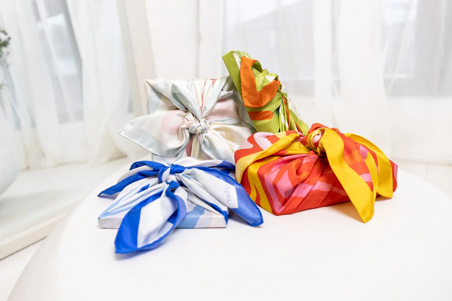 Be The Other gift boxes wrapped in a collection of assorted silk scarves
