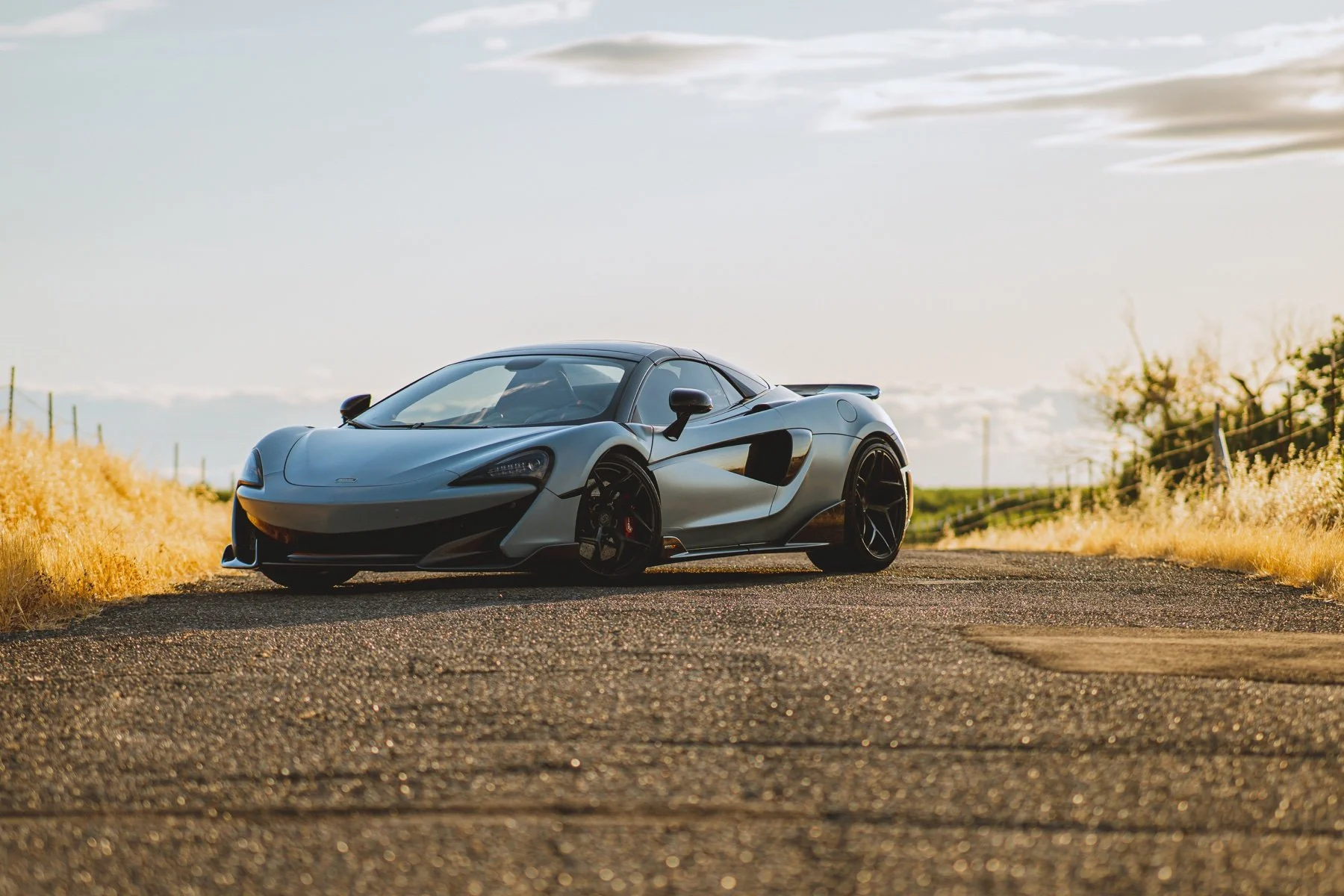 Silver McLaren 600 LT Spider in a three-quarter view on a sunlit country road