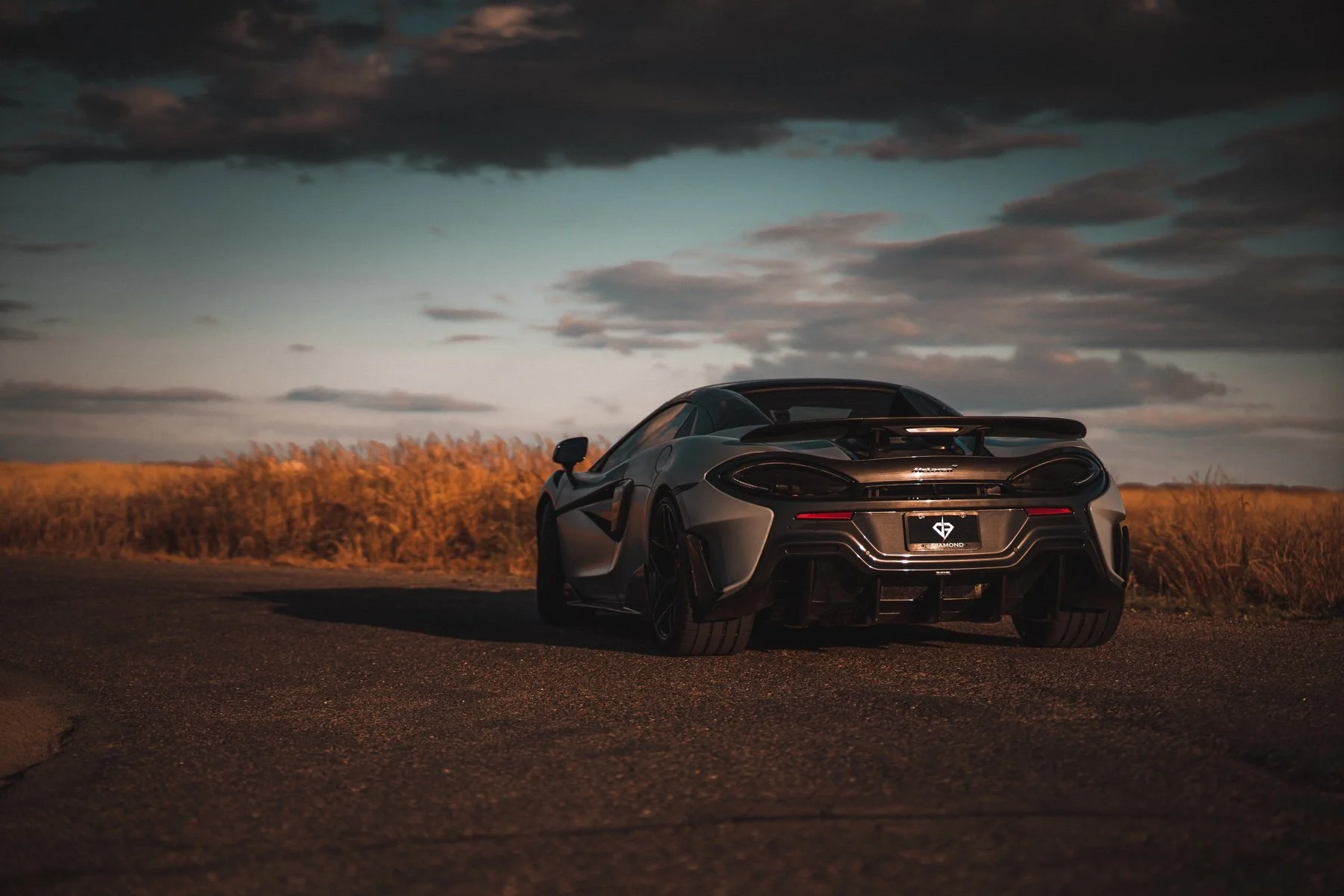 Rear three-quarter view of a McLaren 600 LT Spider against a dramatic evening sky