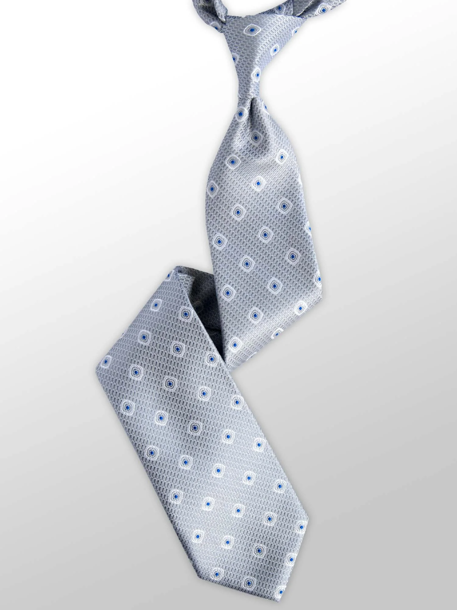 Light gray tie with a small pattern of blue and white circles and a grid-like design, draped over a white surface.