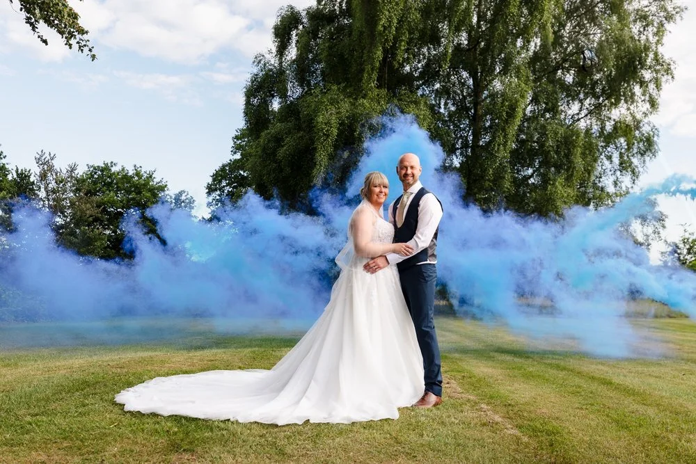 Bride and groom with blue smoke bomb portraits in the grounds of Hogarths Stone Manor