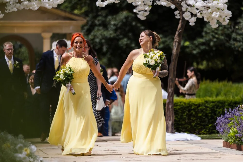 Bridesmaids in yellow dresses walking up the aisle at Rowton Castle's outdoor wedding ceremony