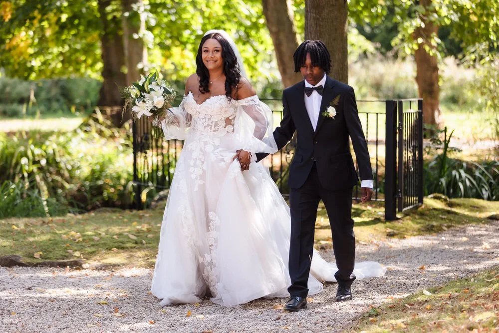 Bride holding her bouquet and walking with her son ahead of the ceremony at Hogarths Hotel Solihull.