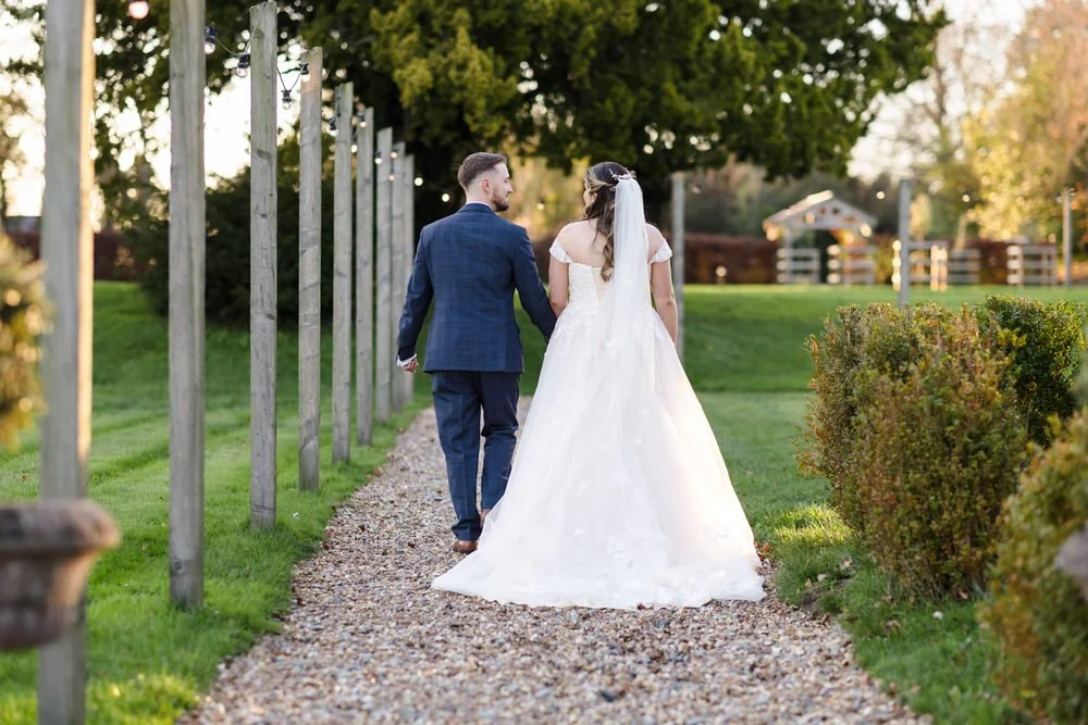 Bride and groom walking on tree-lined pathway at Bredenbury Court Barns estate