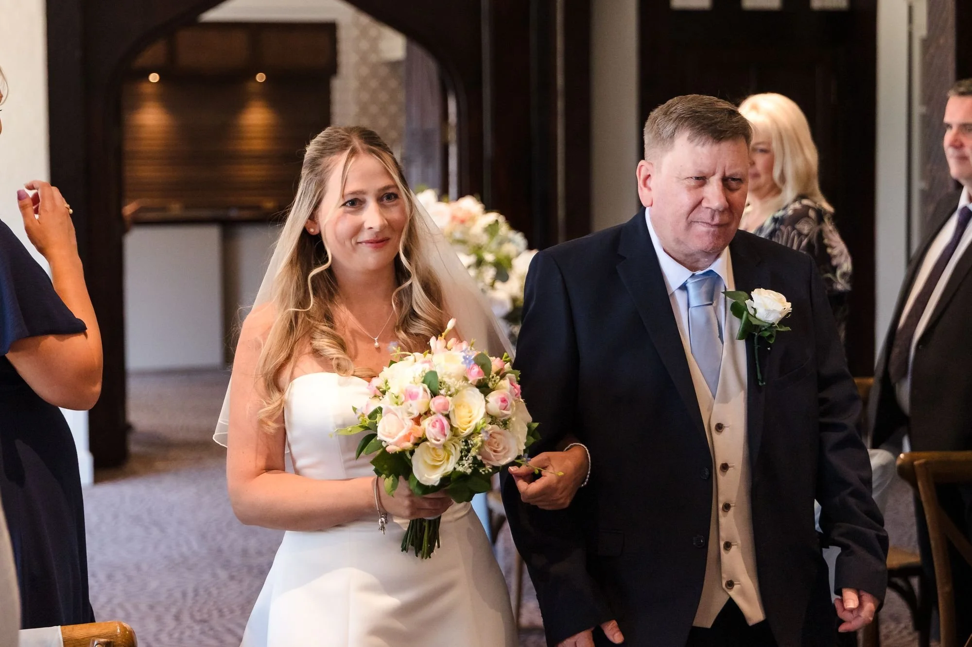 Cheryl smiling as she is walked down the aisle into the Drawing Room at Hogarths Stone Manor