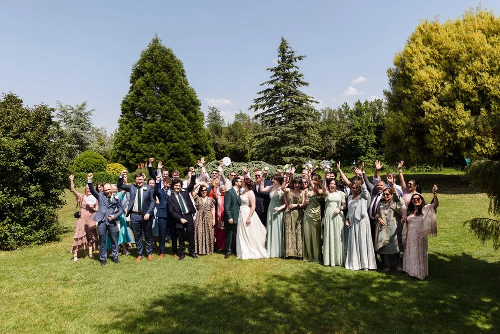 Wedding guests raising their arms in celebration on the lawn at Huntsmill Farm during a group photo.