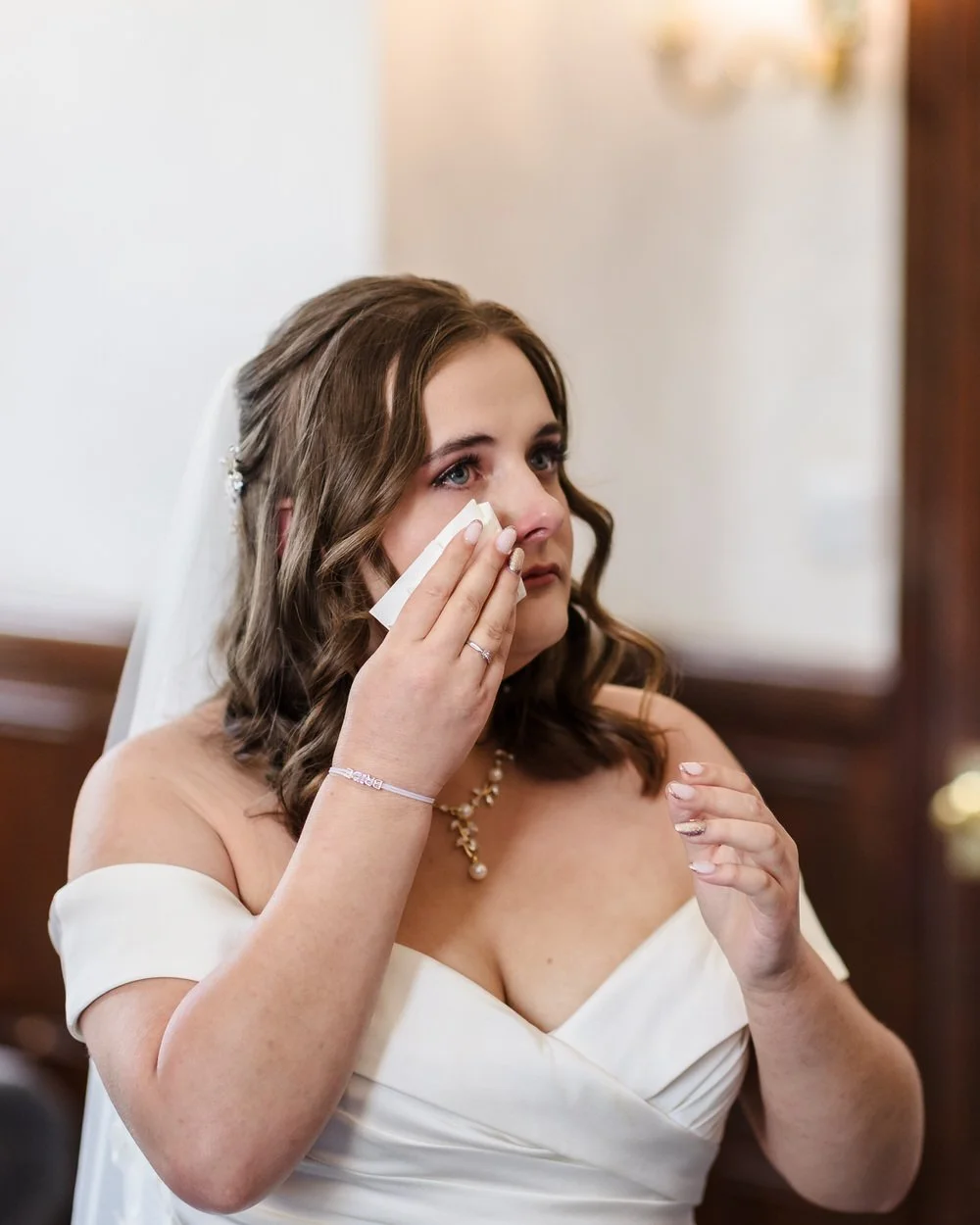 Bride wipes away a happy tear during the ceremony at Karma Salford Hall, in an off-the-shoulder gown and veil.
