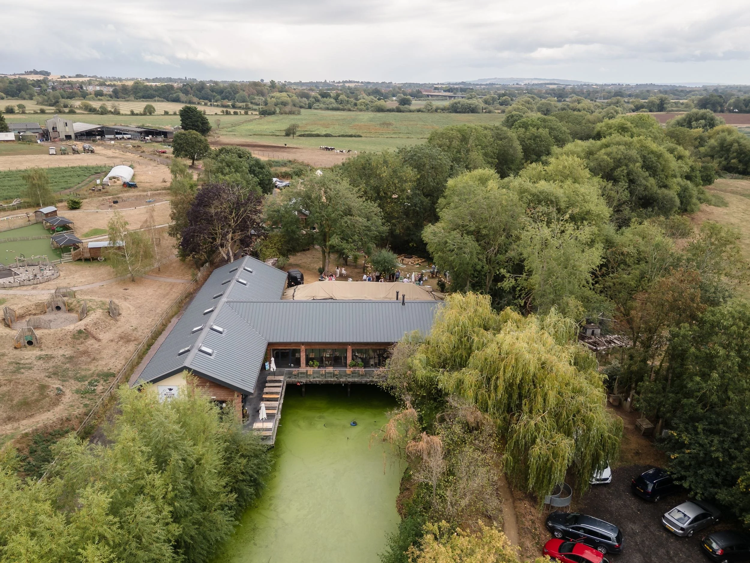 Aerial view of Bennetts Willow Barn on its farm at Lower Wick, Worcester, with the barn beside a willow-fringed pond and fields beyond
