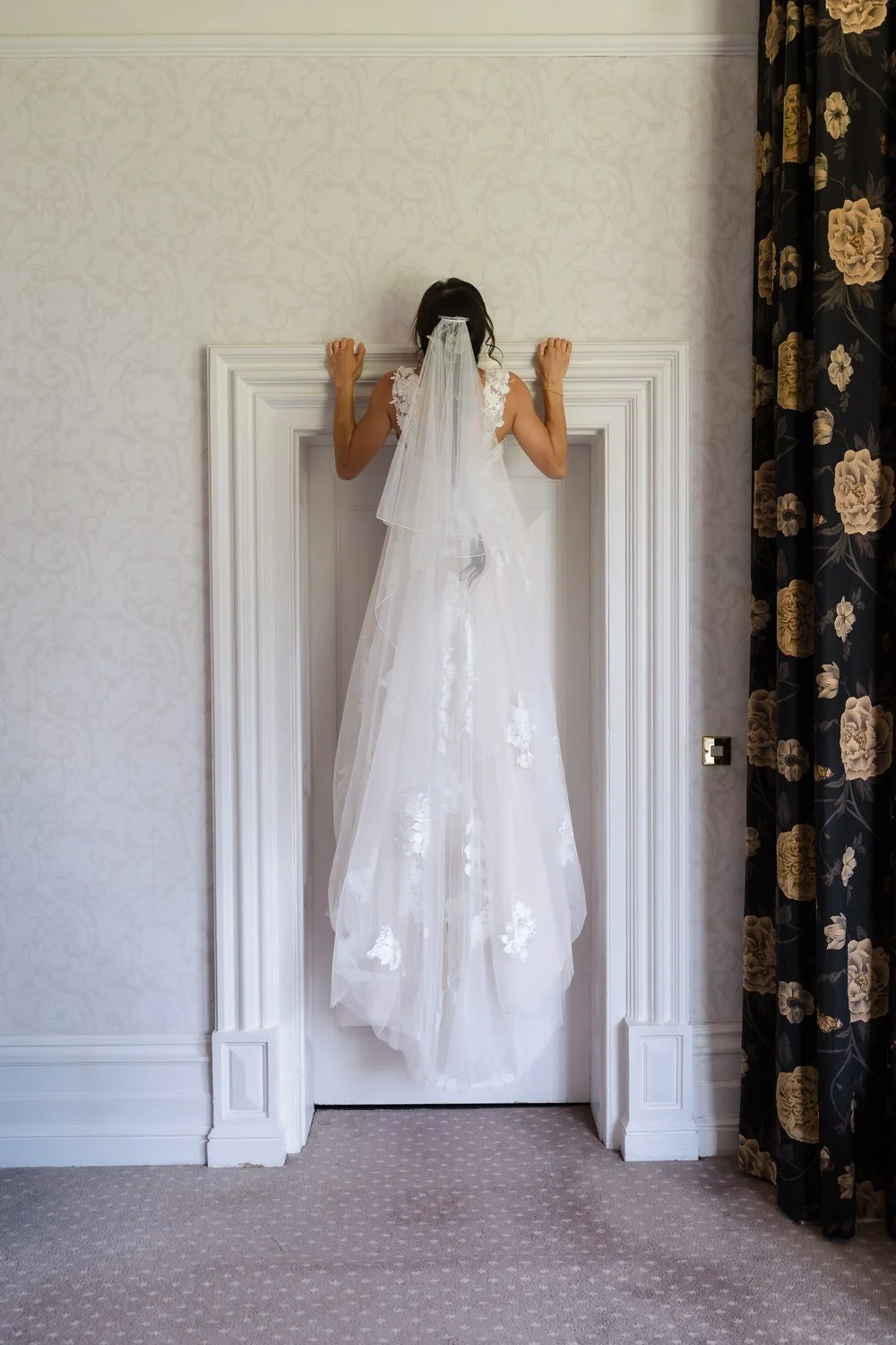 Bride Christine in her veil framed in a doorway during preparation at The Welcombe Hotel, Warwickshire.