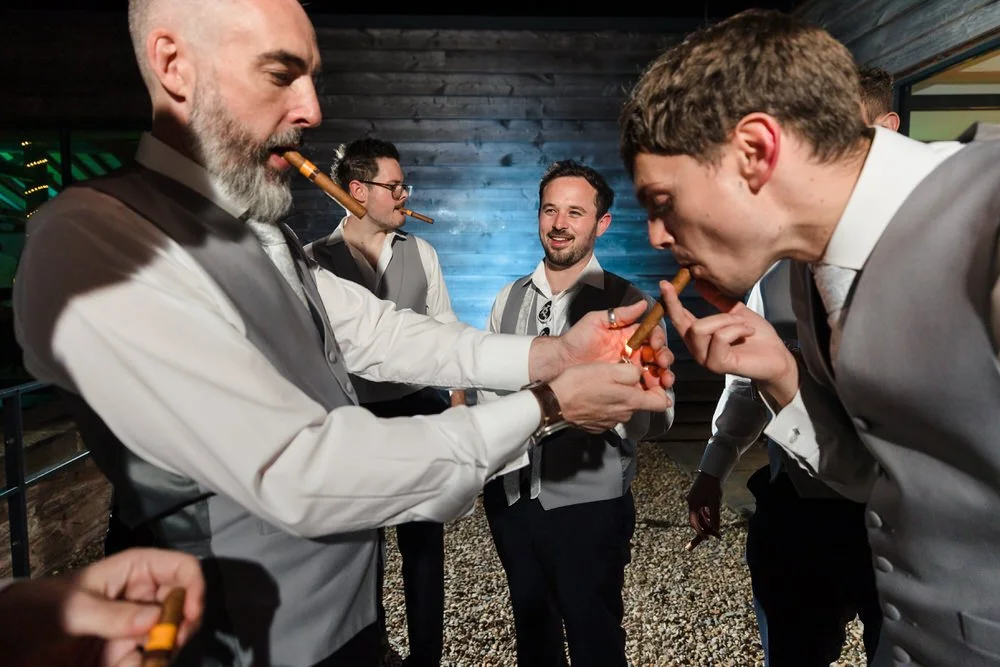 Candid groomsmen celebration with cigars at Bredenbury Court Barns Herefordshire wedding reception