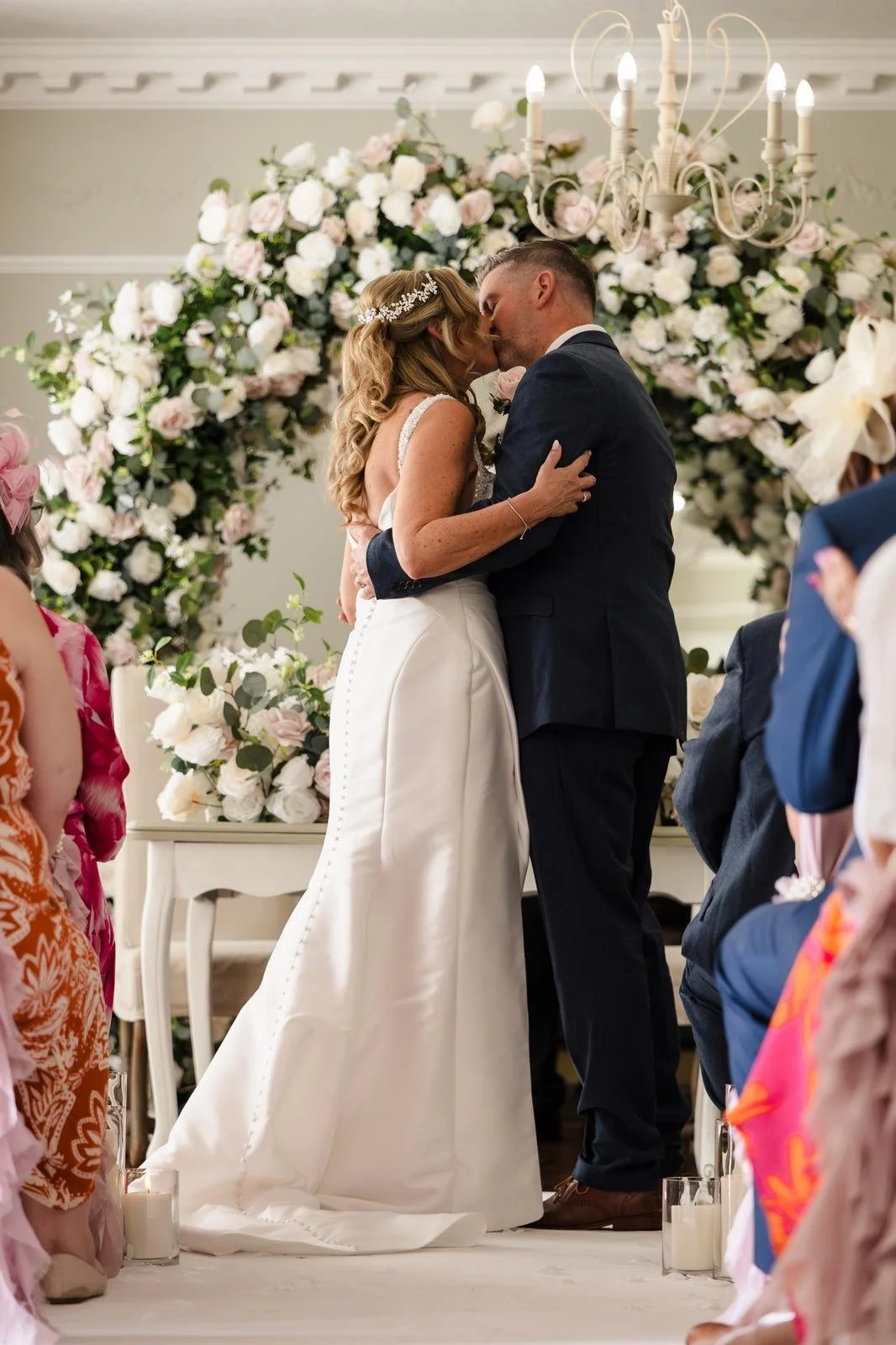 Charlotte and Richard's ceremony embrace under the floral arch at Ashton Lodge Country House wedding photography by Once in a Lifetime Photography