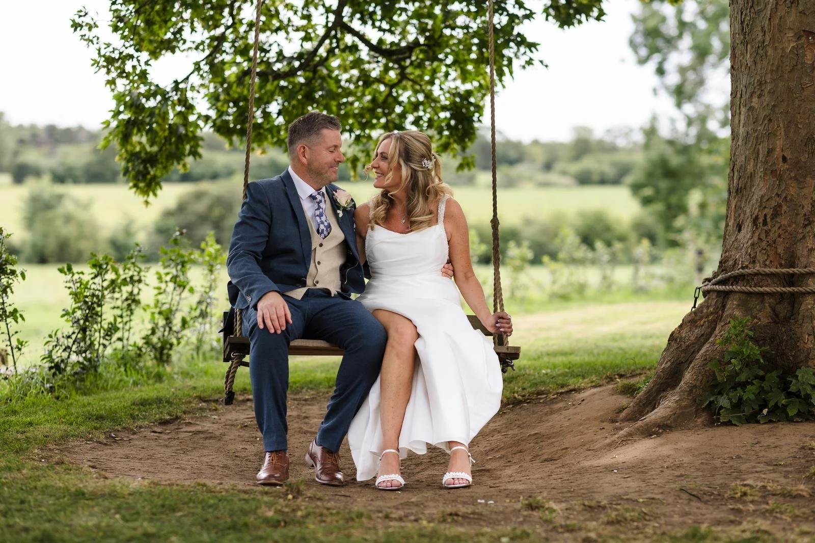 Bride and groom sharing a moment on the wooden garden swing at Ashton Lodge Country House wedding photography by Once in a Lifetime Photography