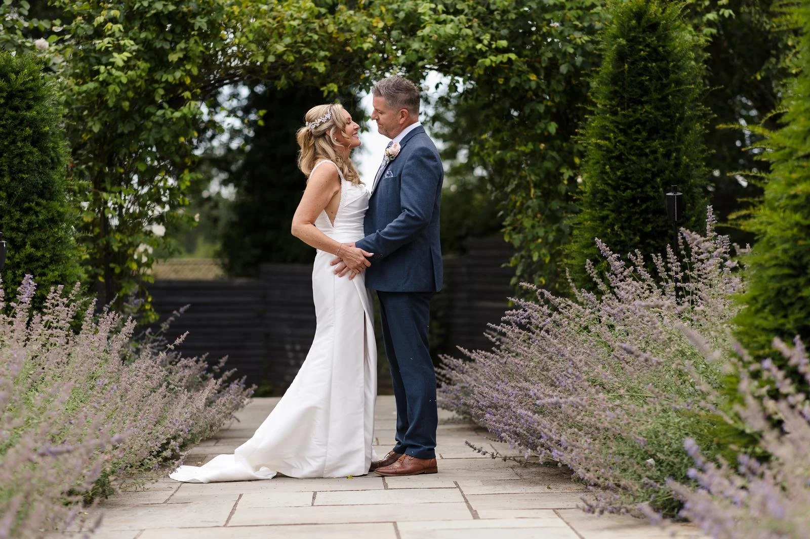 Charlotte and Richard walking the garden hedge path at Ashton Lodge Country House wedding photography by Once in a Lifetime Photography