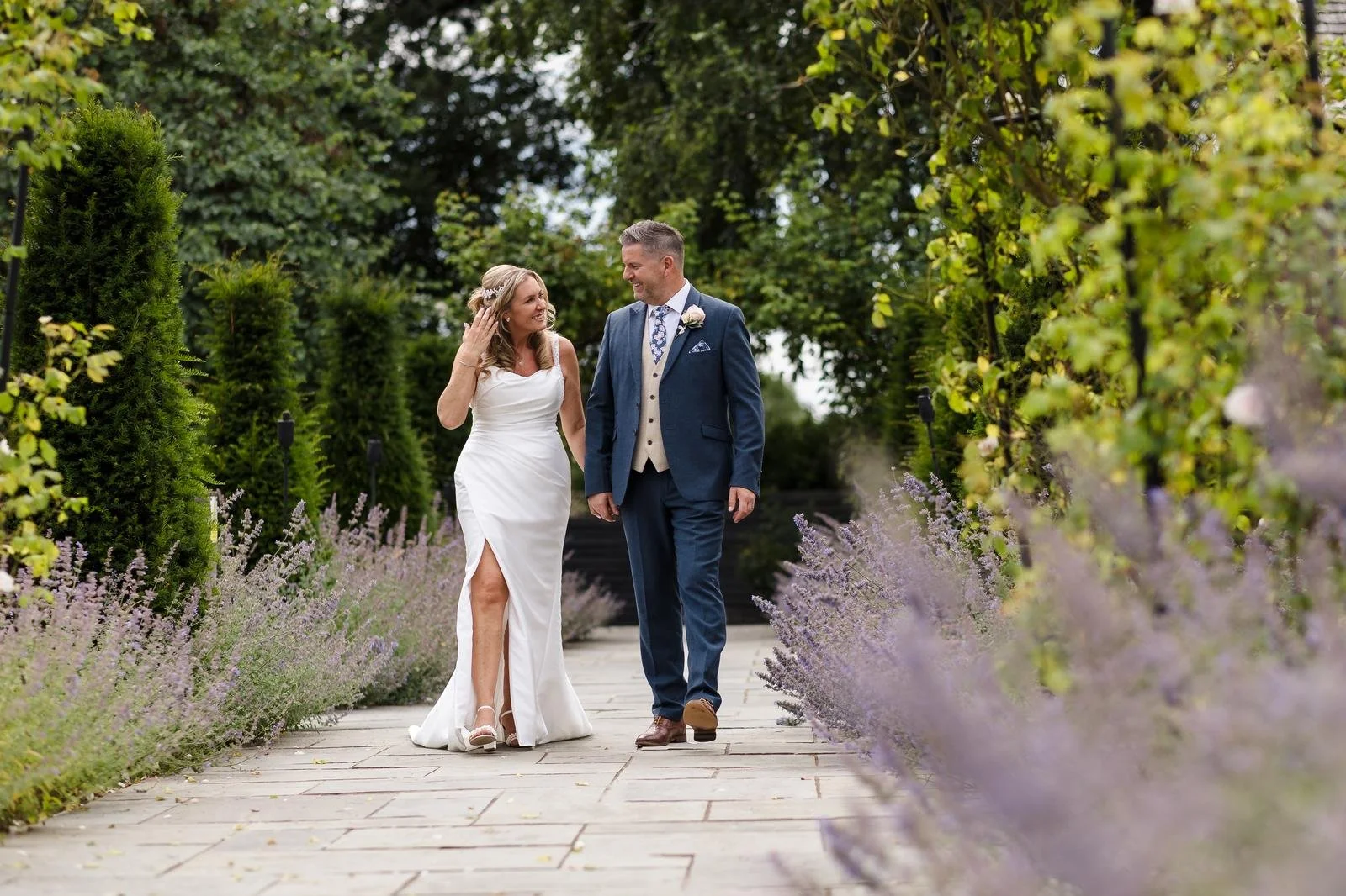 Charlotte and Richard walking the lavender garden path at Ashton Lodge Country House wedding photography by Once in a Lifetime Photography