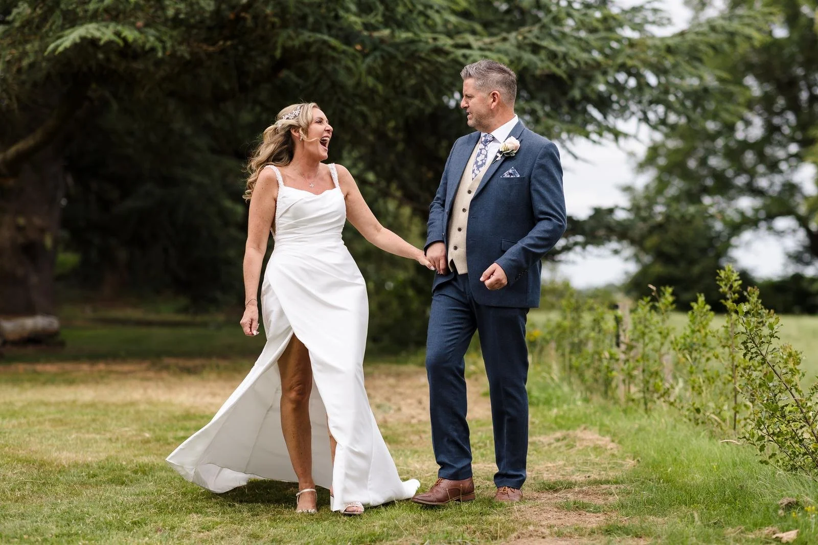 Charlotte and Richard walking the lawn path at Ashton Lodge Country House wedding photography by Once in a Lifetime Photography
