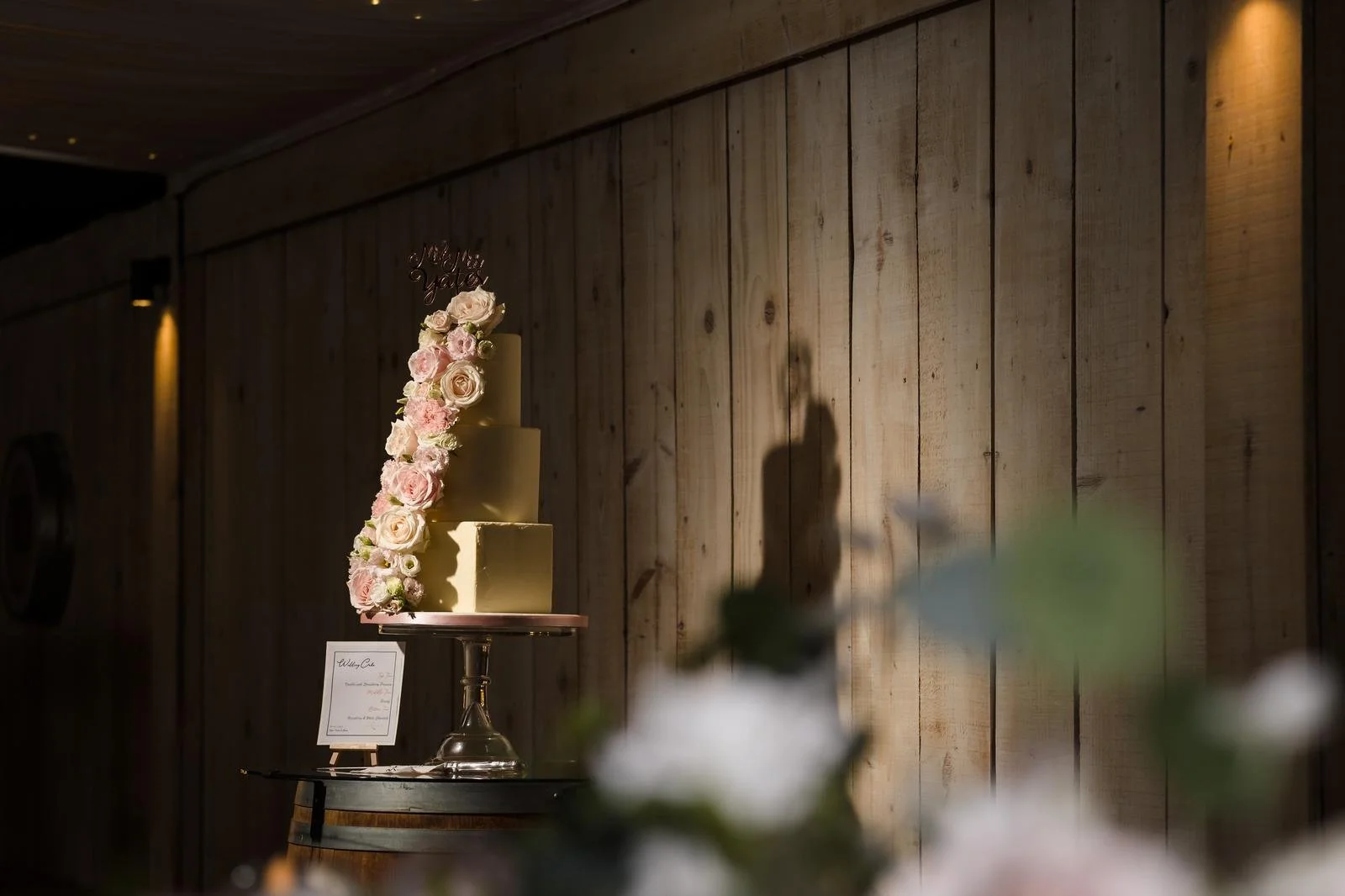 Wedding cake displayed against the marquee’s wood-panelled wall at Ashton Lodge Country House wedding photography by Once in a Lifetime Photography